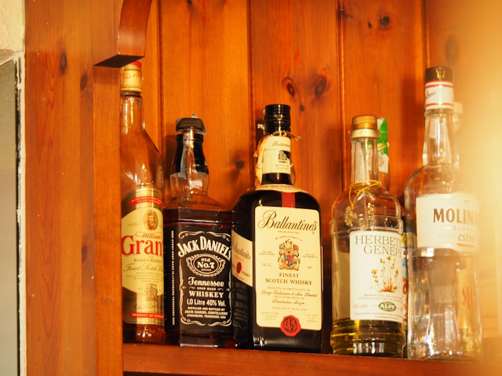 A rustic wooden shelf filled with diverse bottles of wine and spirits under warm lighting