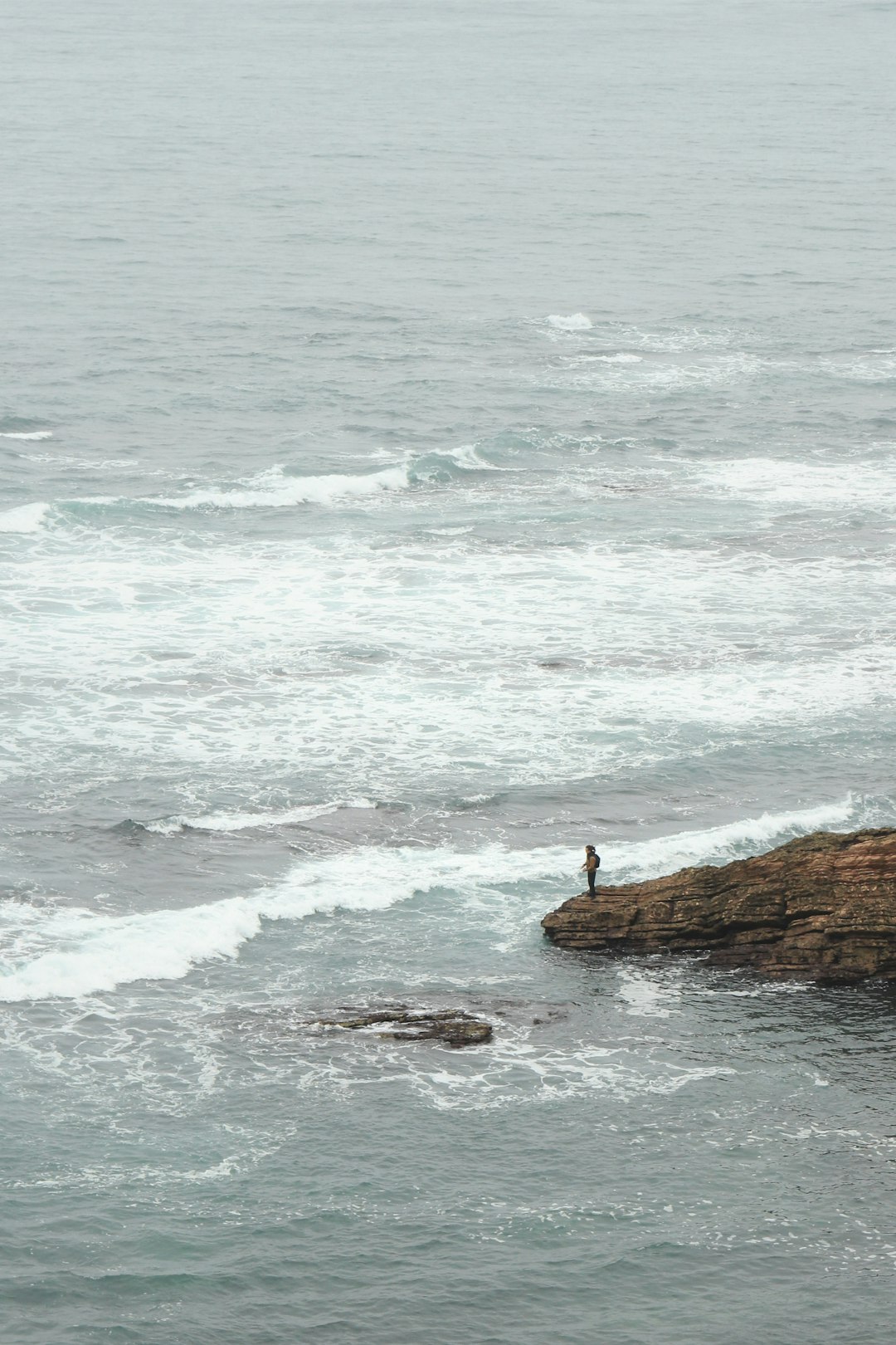 person standing on coastal rock during daytime
