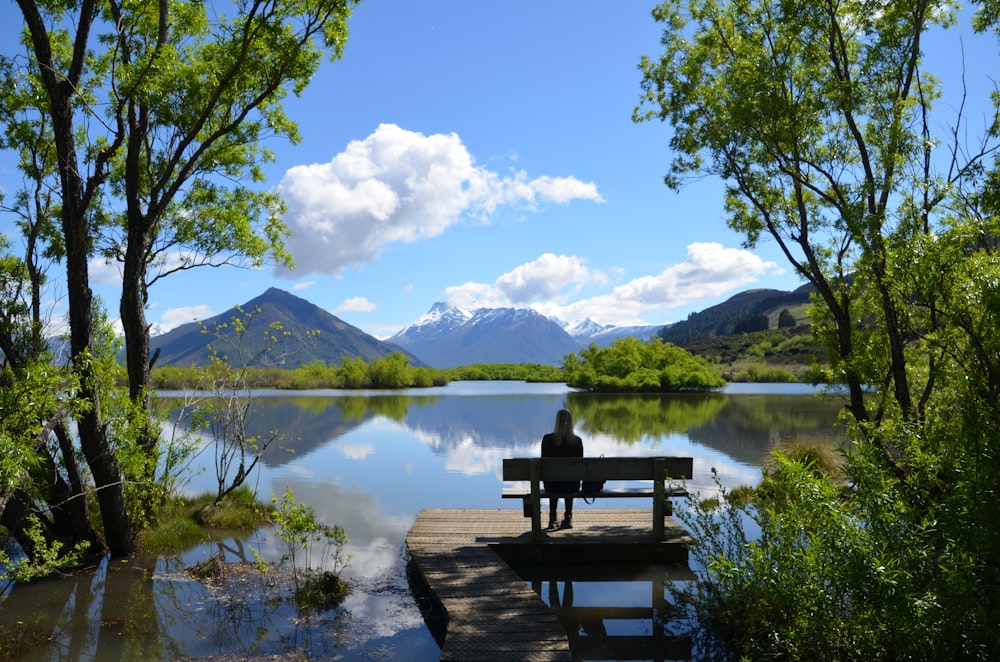 mulher sentada no banco perto do lago