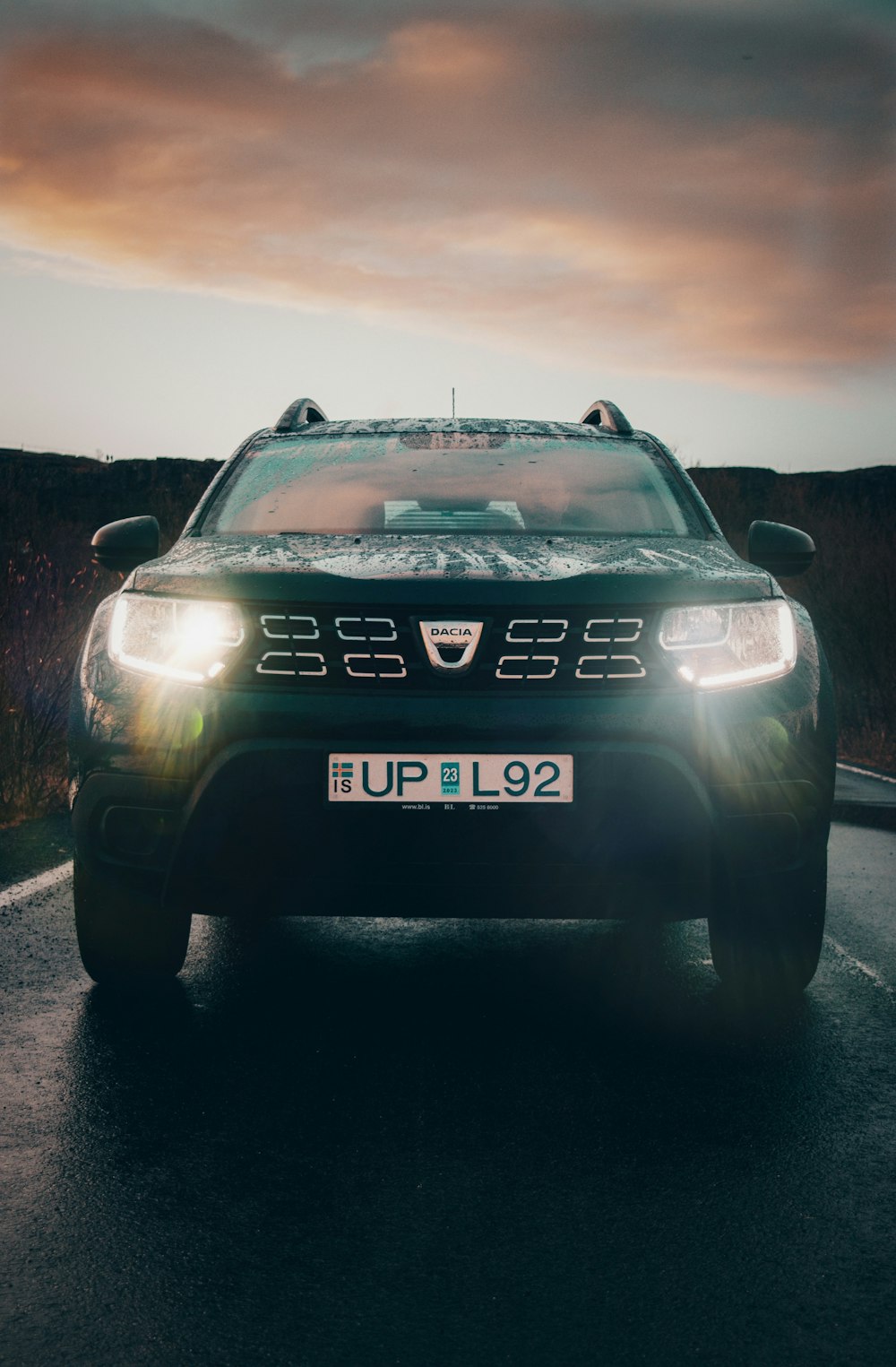 a car driving down a road with a cloudy sky in the background