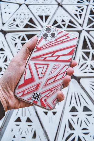 Vibrant geometric pattern phone case held in a hand outdoors