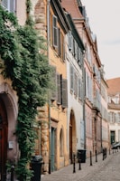 A quiet street lined with weathered stone buildings and colorful shutters.