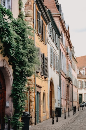 A quiet street lined with weathered stone buildings and colorful shutters.
