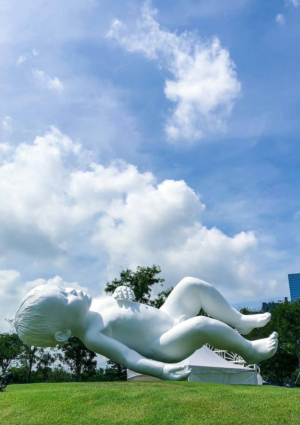 baby floating statue on green field under white and blue sky