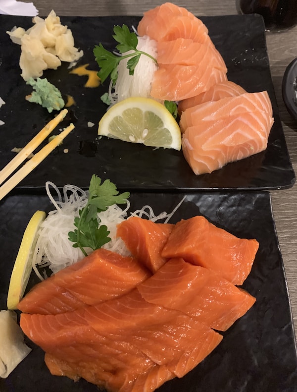 Salmon fish near sliced lemon, noodles, and parsley