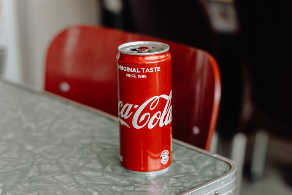 Coca-Cola original taste soda can on edge of gray table
