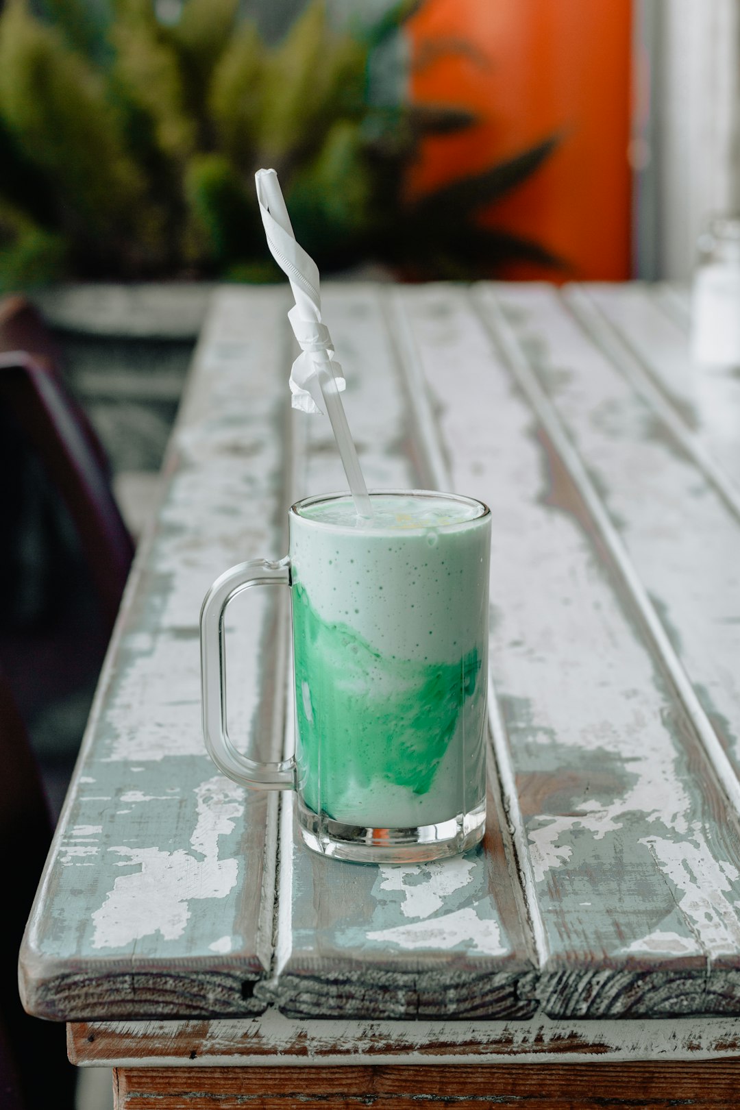 milk tea in clear glass mug on edge of white wooden table