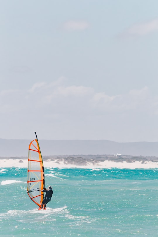 man riding on the black and orange boat photograph in Struisbaai South Africa