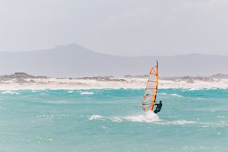 Wind surfer gliding over crystal clear blue water.
