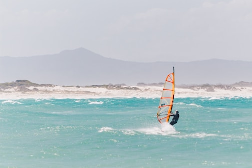 Wind surfer gliding over crystal clear blue water.