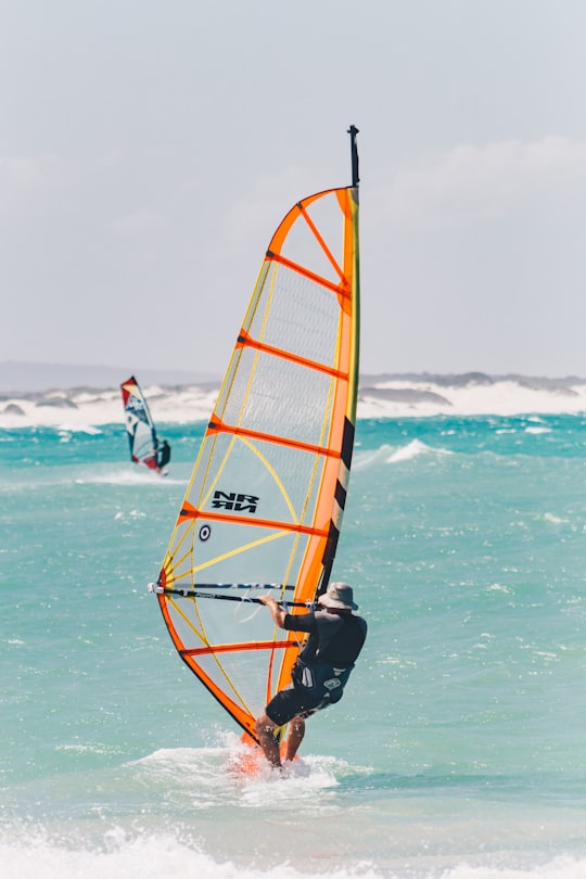 man wearing black shirt and hat windsurfing under white sky in Struisbaai South Africa
