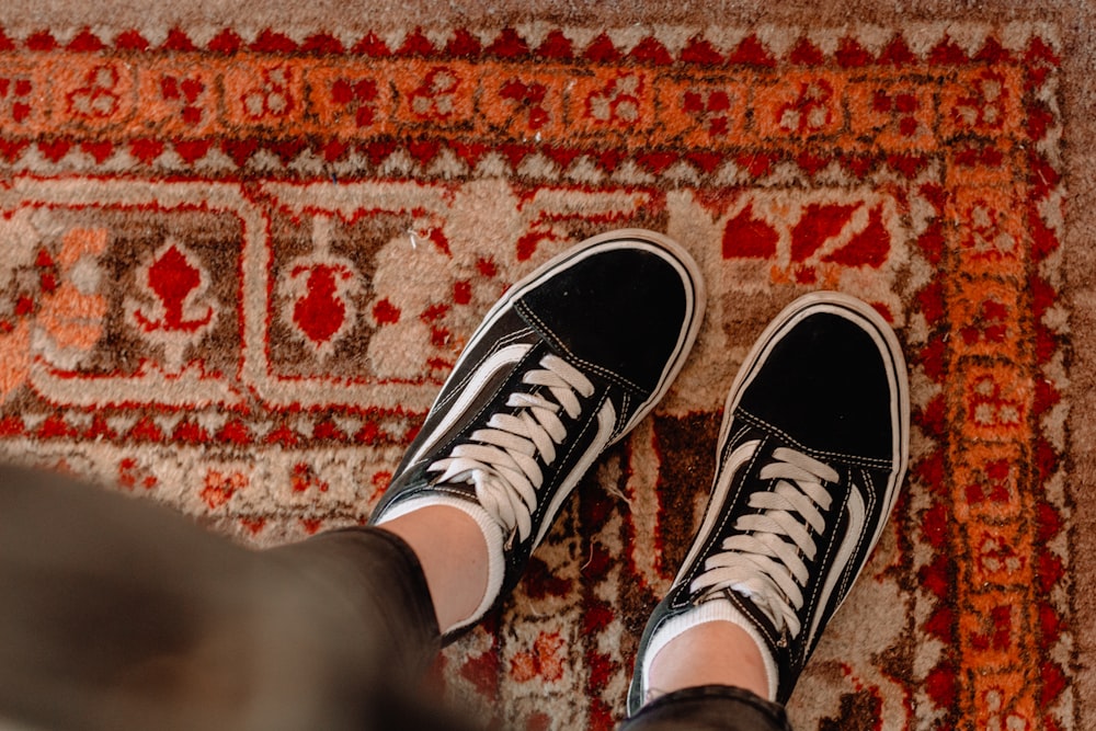 person wearing black-and-white Vans low-top sneakers standing