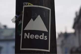 selective focus photography of white and black Needs signage