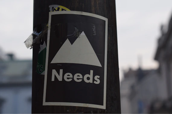 selective focus photography of white and black Needs signage
