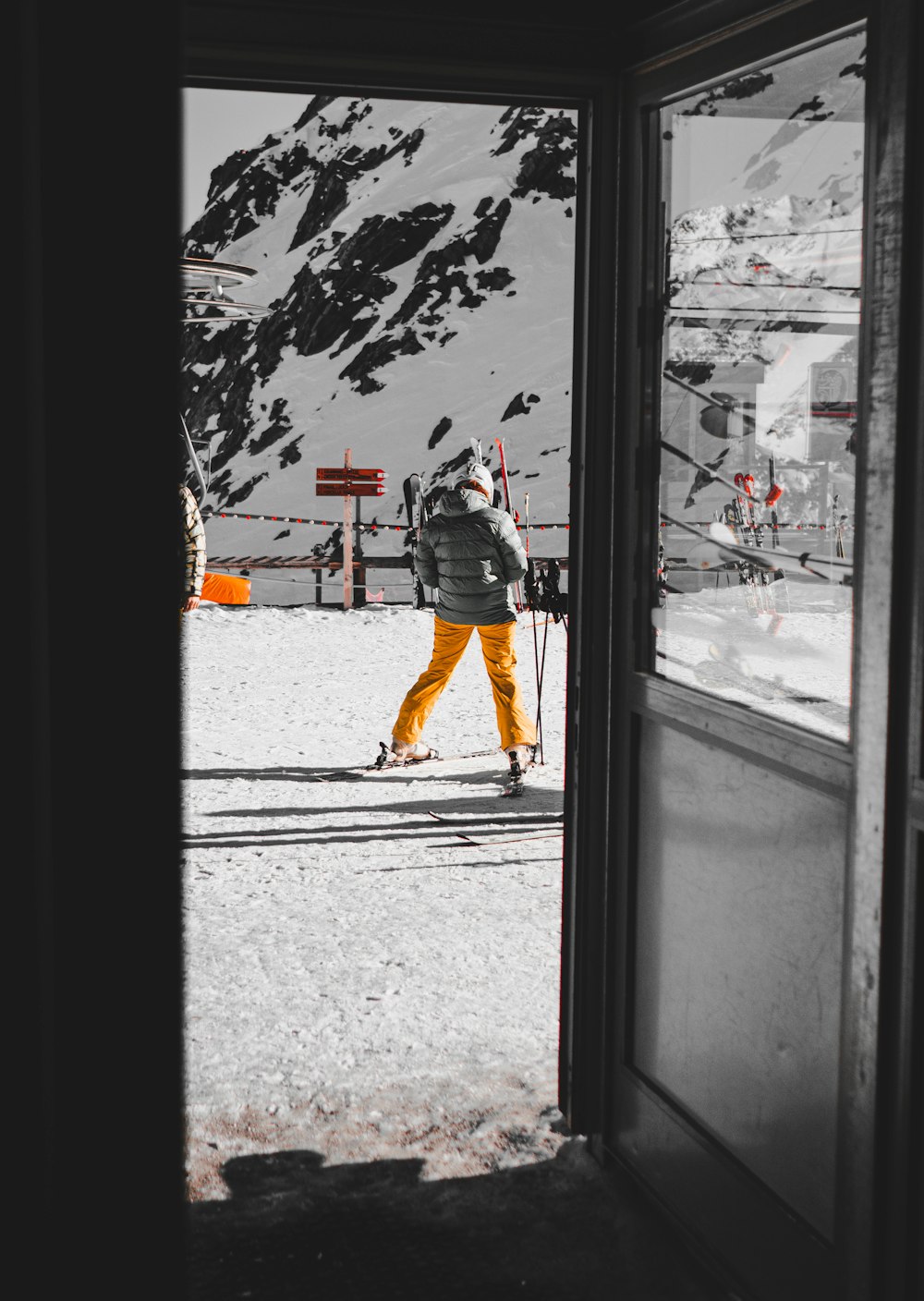 person wearing gray bubble jacket and yellow pants standing on snowy field during daytime