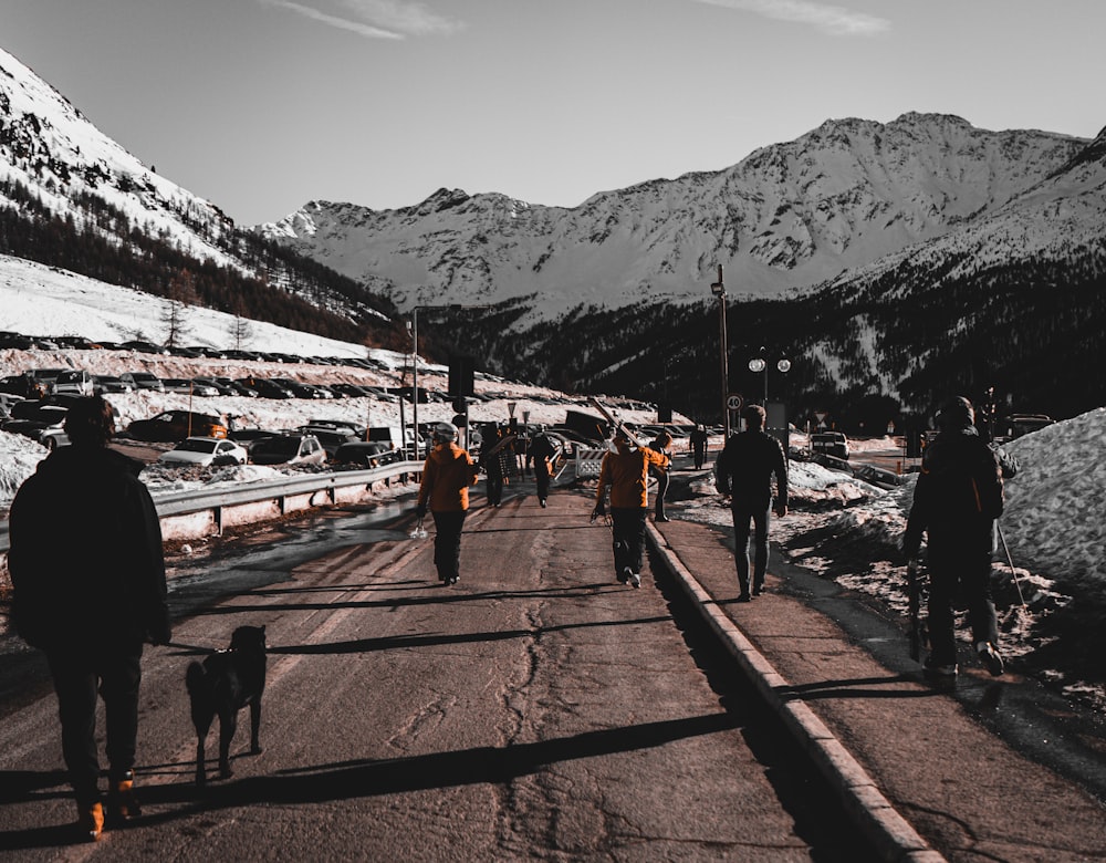 people walking on road near field covered with snow viewing mountain during daytime