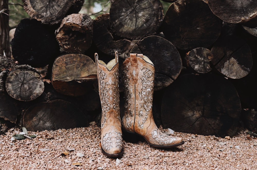 pair of brown leather cowboy boots near firewood