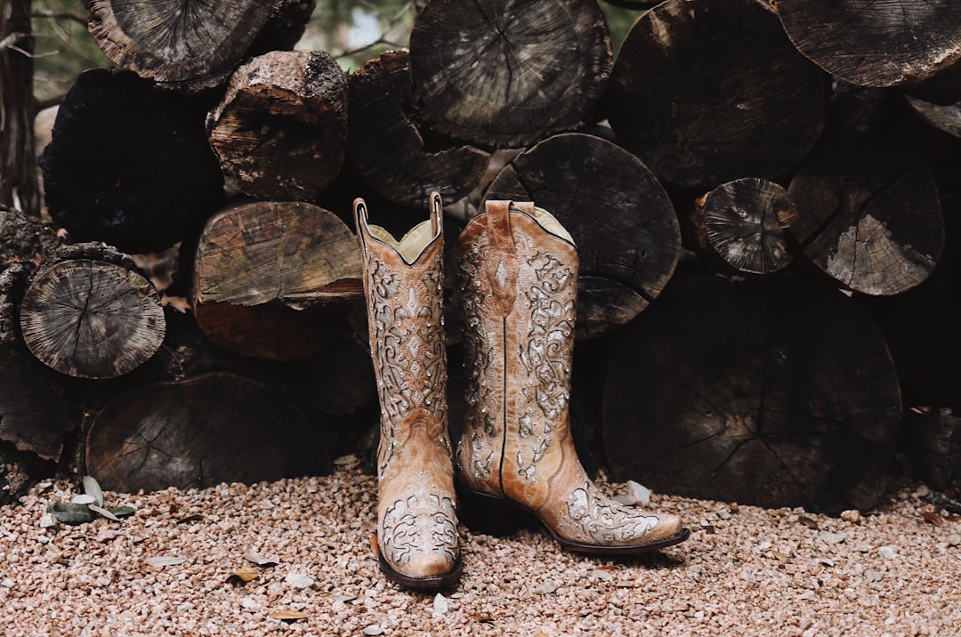 pair of brown leather cowboy boots near firewood