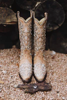 Close-up of handcrafted cowboy boots resting on rustic wooden floor.