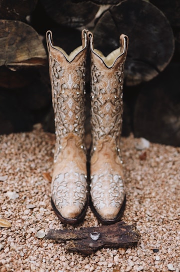 A stylish pair of women's cowboy boots displayed on a rustic wooden surface.