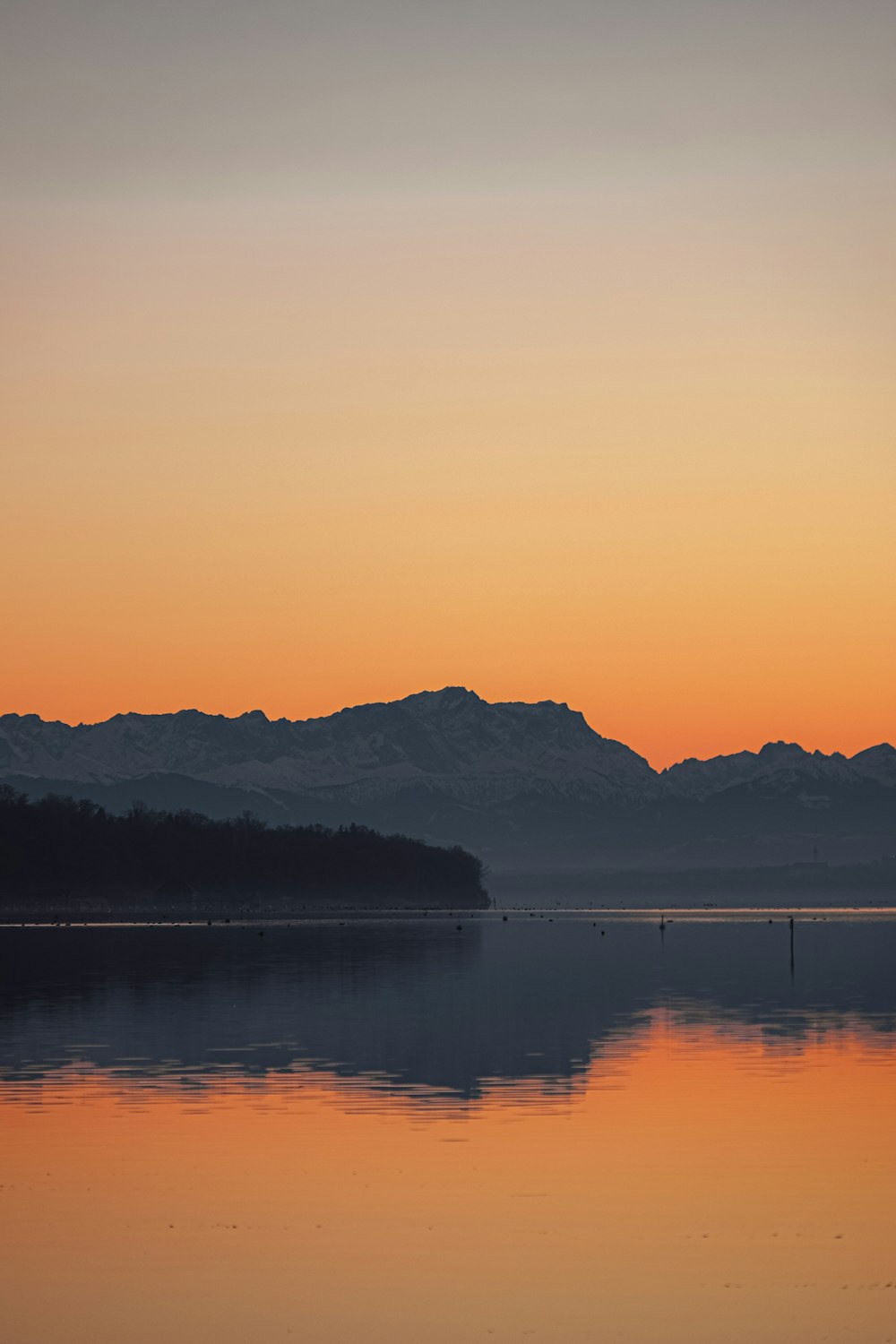 silhouette photography of a mountain and body of water during golden hour