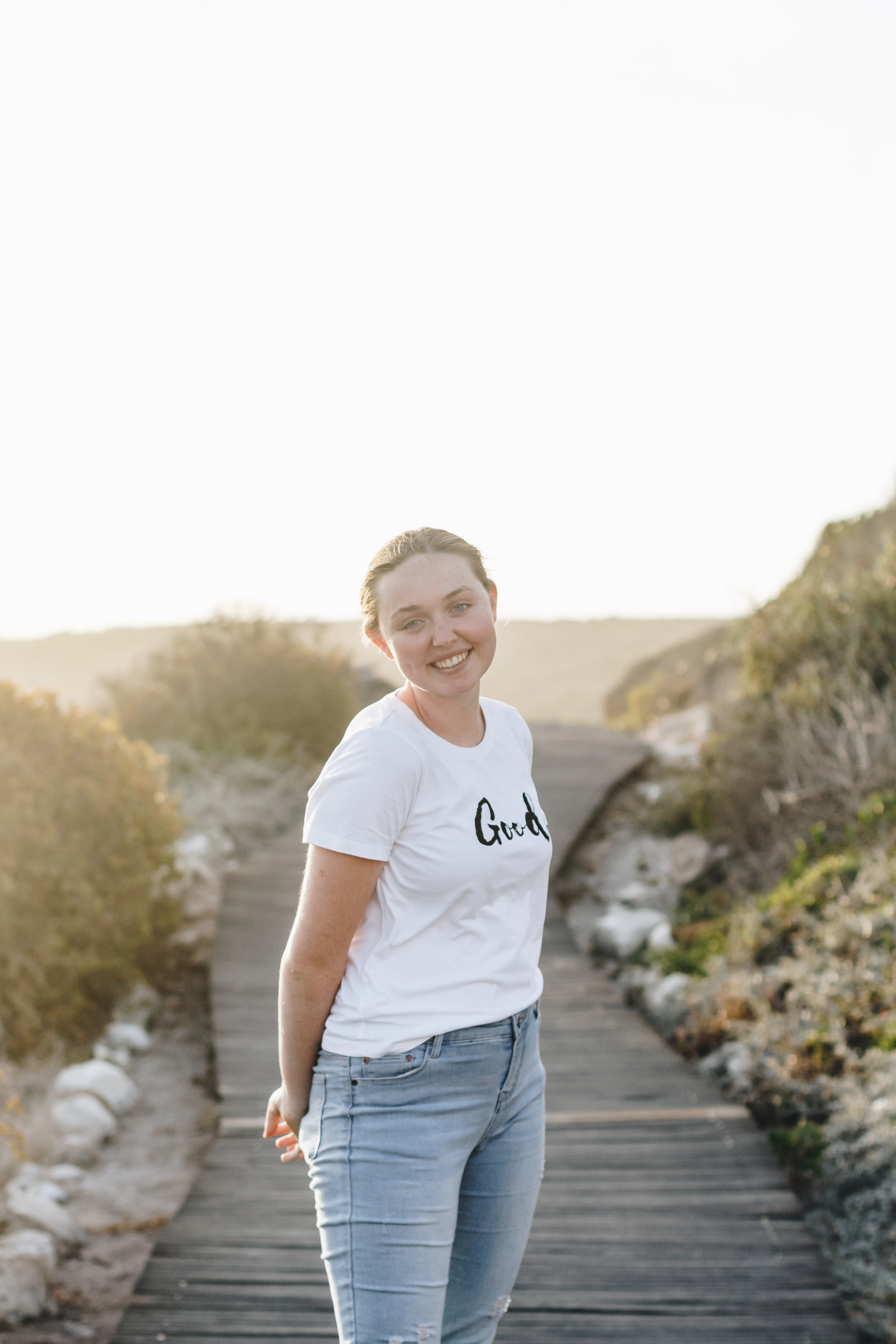 Mulher em uma passarela de praia usando camiseta branca estampada