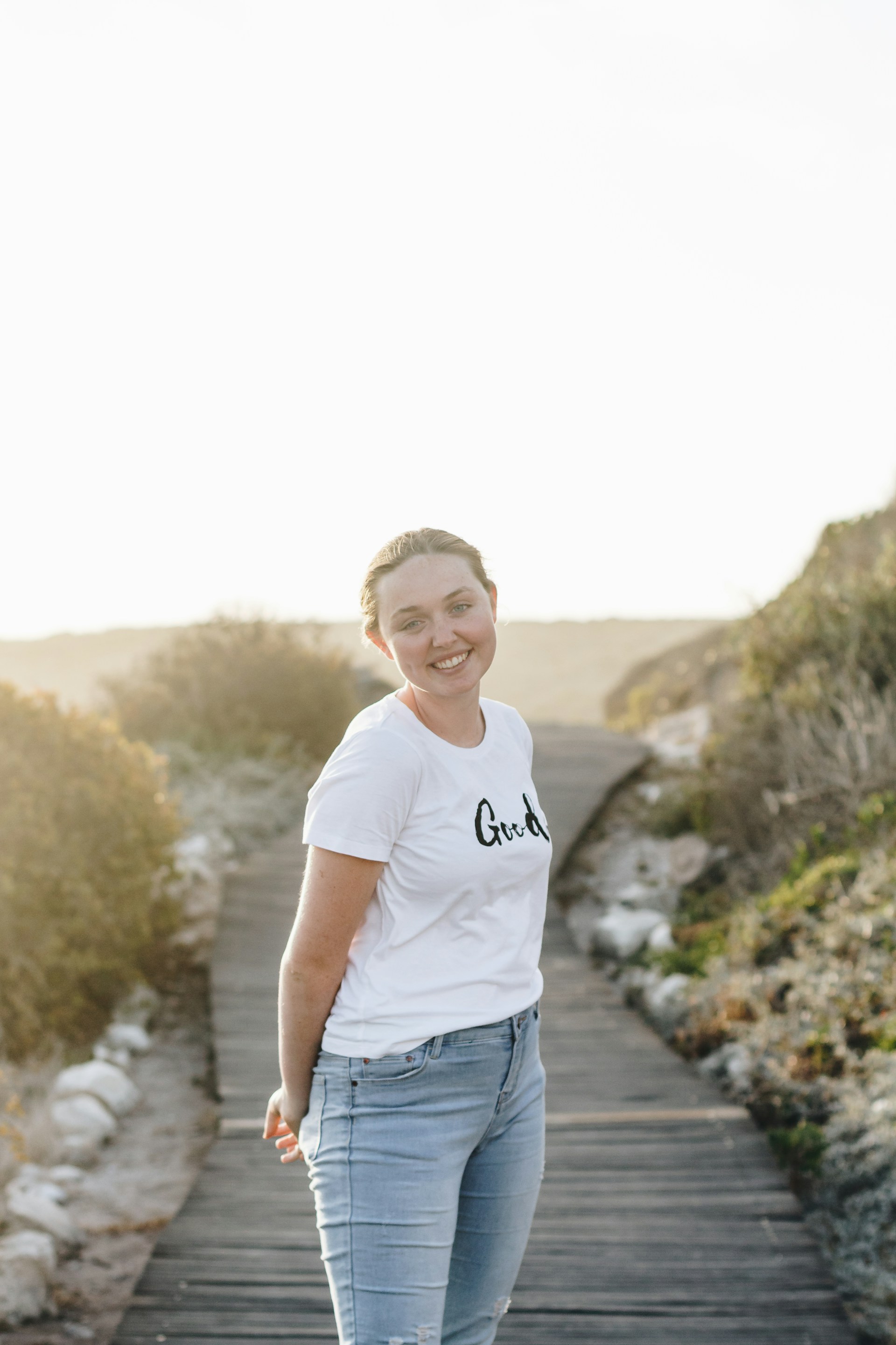 A candid photograph of a person enjoying a sunny day outdoors, smiling and surrounded by nature.