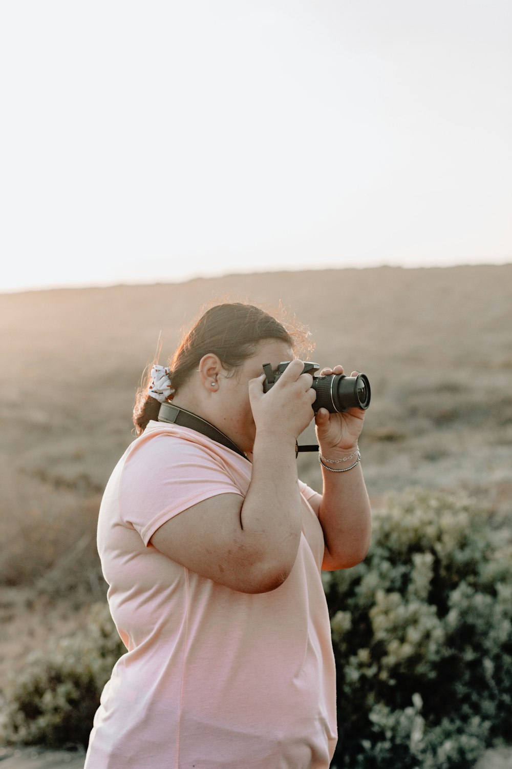 mujer con camiseta rosa de pie mientras toma una foto