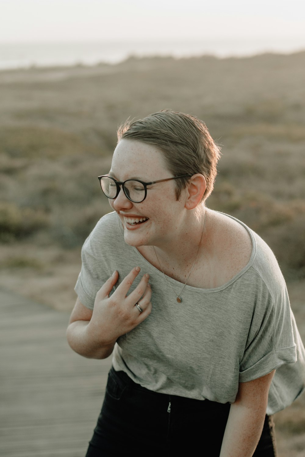 smiling woman wearing eyeglasses and gray top