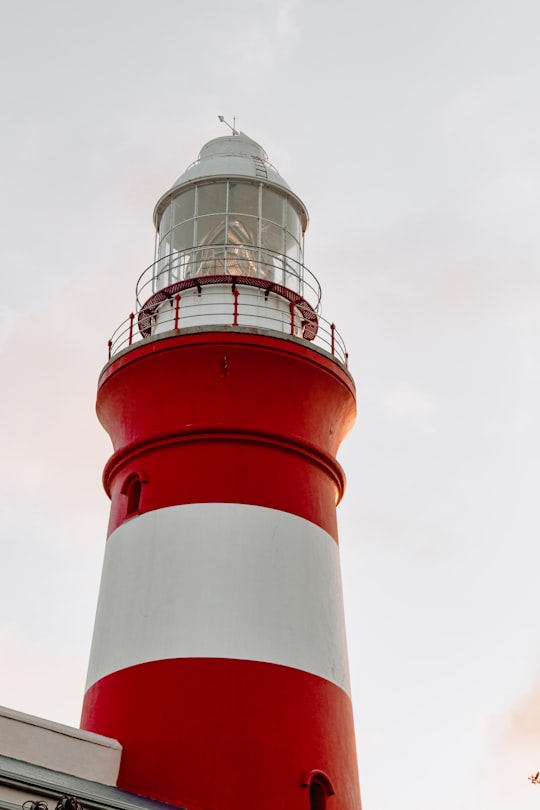low-angle photography of white and red lighthouse during daytime in Cape Agulhas Lighthouse South Africa
