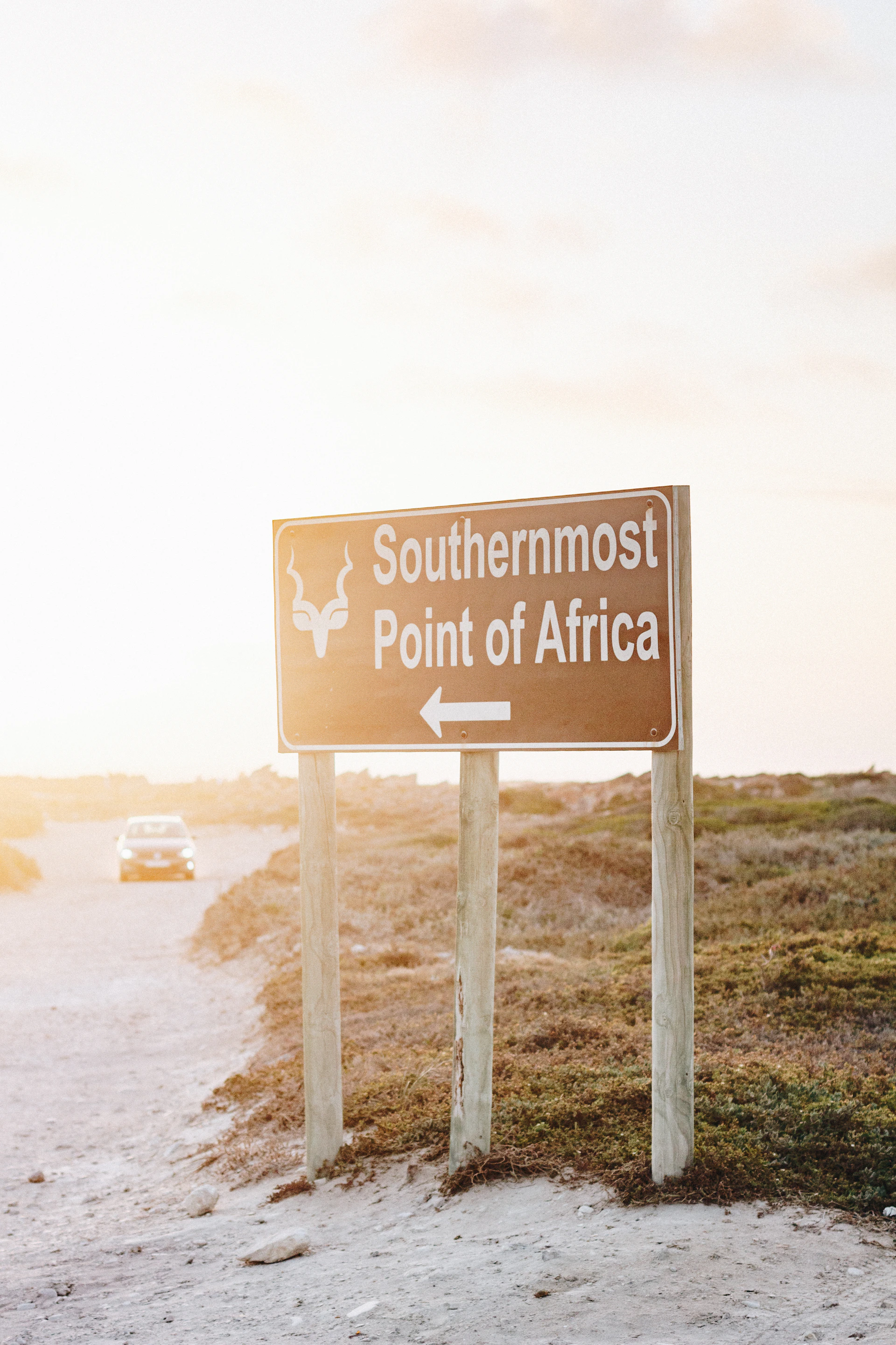 Southermost Point of Africa road sign and white vehicle on road during daytime