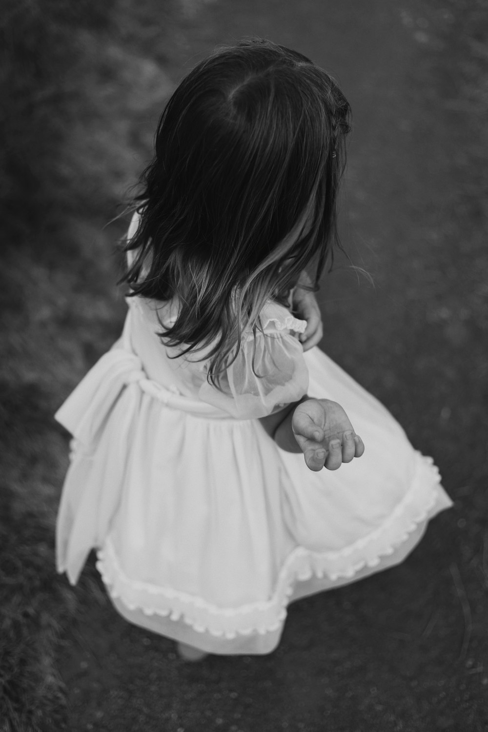 grayscale photography of child wearing dress standing while facing back