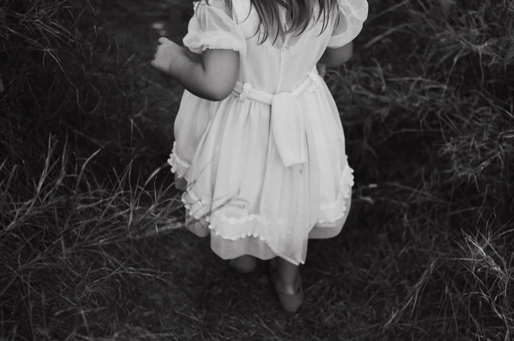 grayscale photography of girl wearing dress standing while facing back