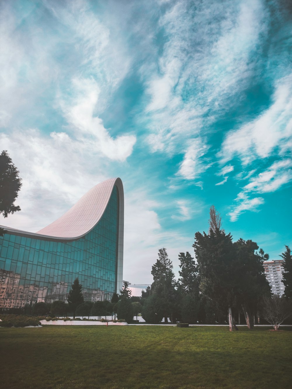 gray building near green trees under cloudy sky