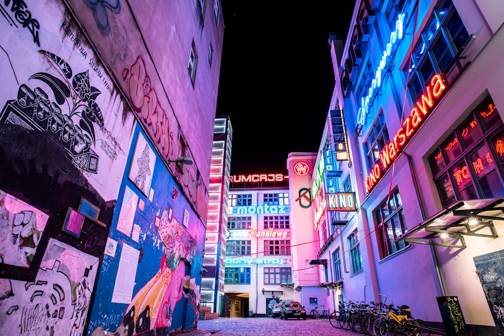 road between buildings with graffiti at night