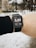 A person is wearing a smartwatch on their wrist, displaying a distance of 5.08 kilometers. The background is a snowy outdoor setting with some trees and buildings visible.