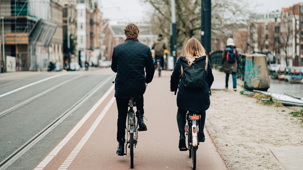 man and woman biking on road viewing buildings during daytime