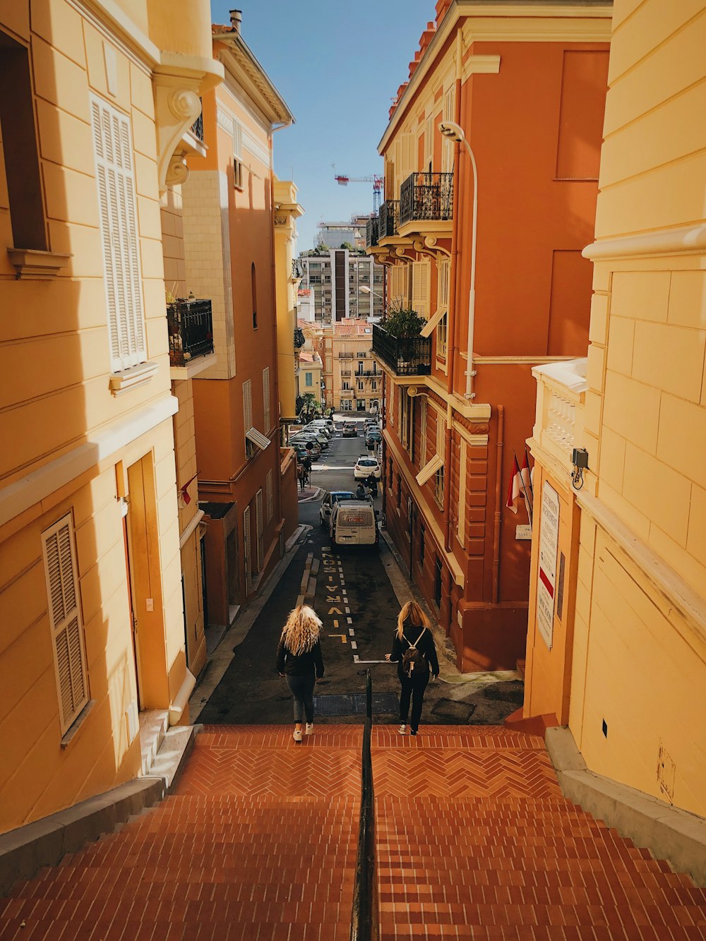 two women walking down the stairs near buildings and road during day