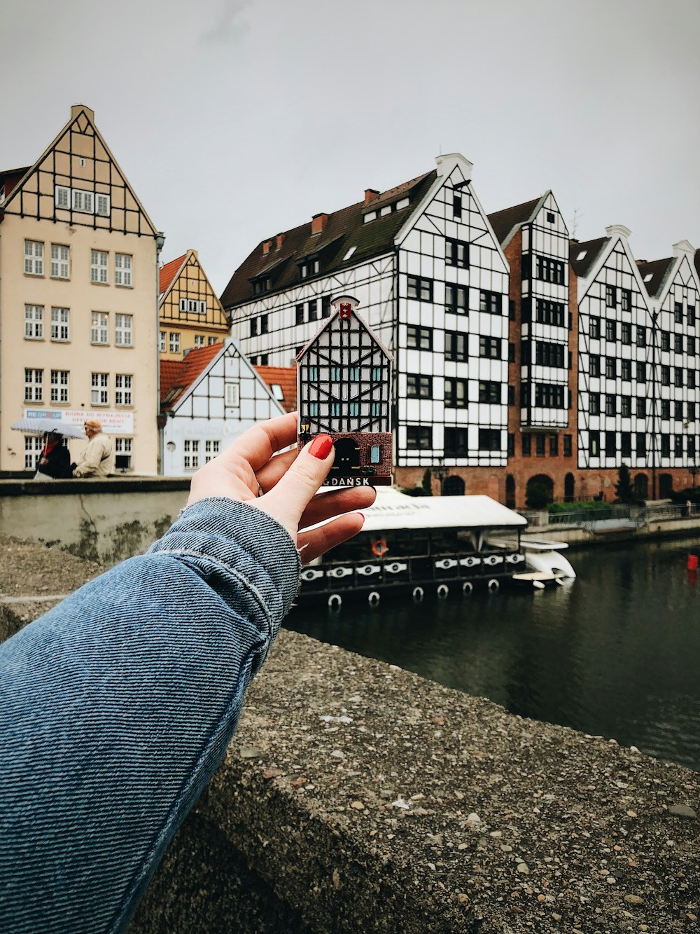 a person's hand holding a piece of paper over a body of water