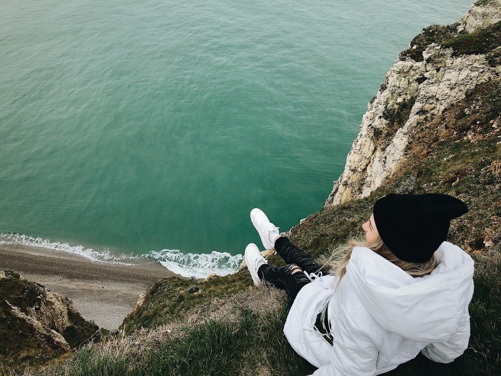 woman sitting on cliff overlooking sea