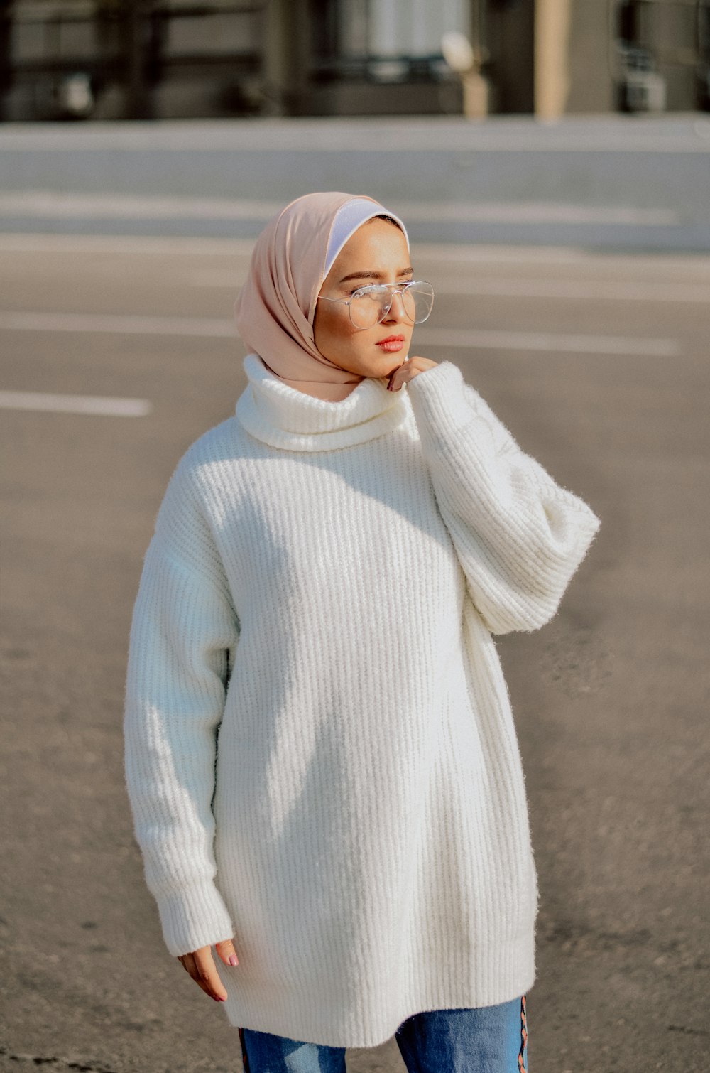 woman wearing white sweater, beige hijab headscarf, and eyeglasses standing on pathway during daytime