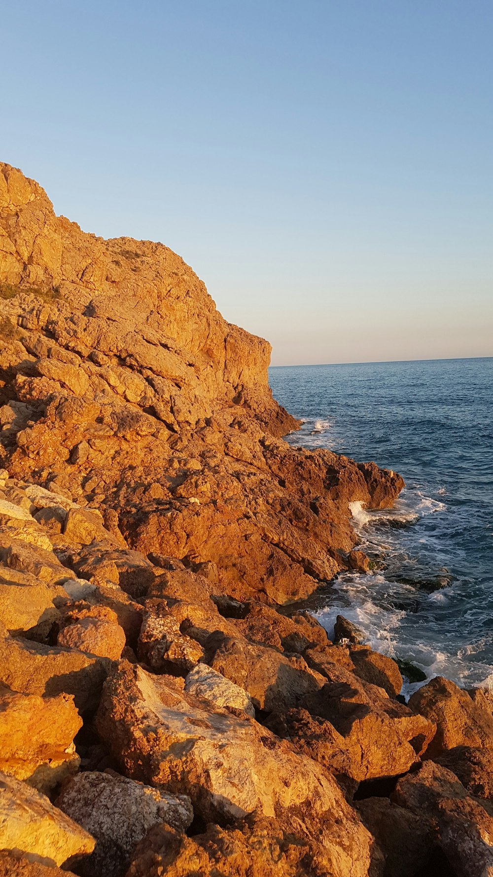 landscape photography of cliff viewing blue body of water during daytime