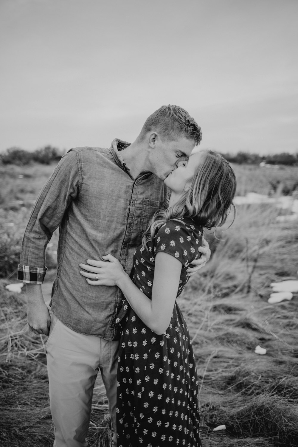 grayscale photography of man and woman standing while kissing on lips