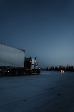 white and black freight truck traveling on road