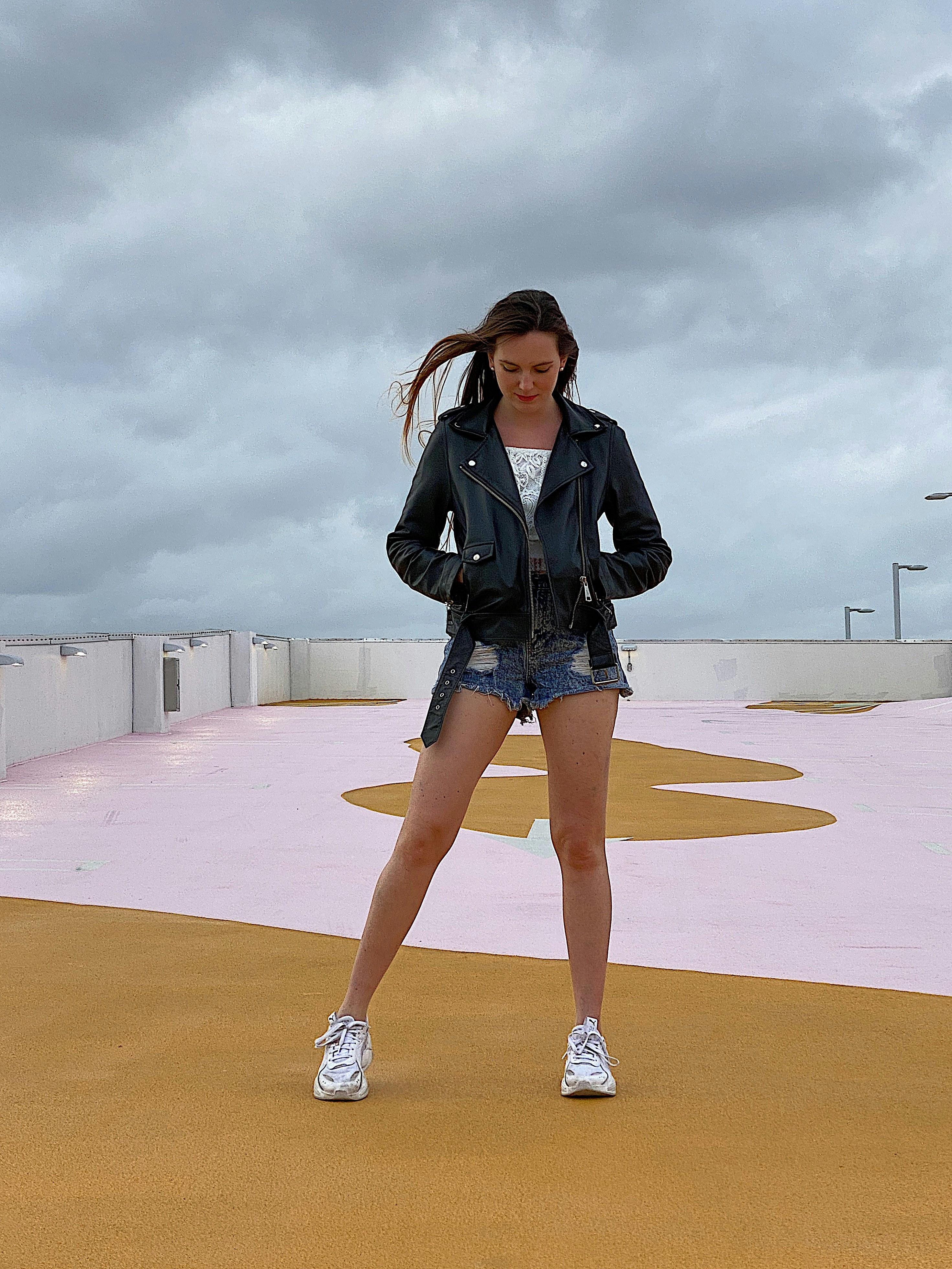 Woman in black leather jacket and blue denim jeans sitting on ground ...