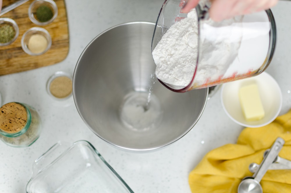 person pouring floor in mixing bowl