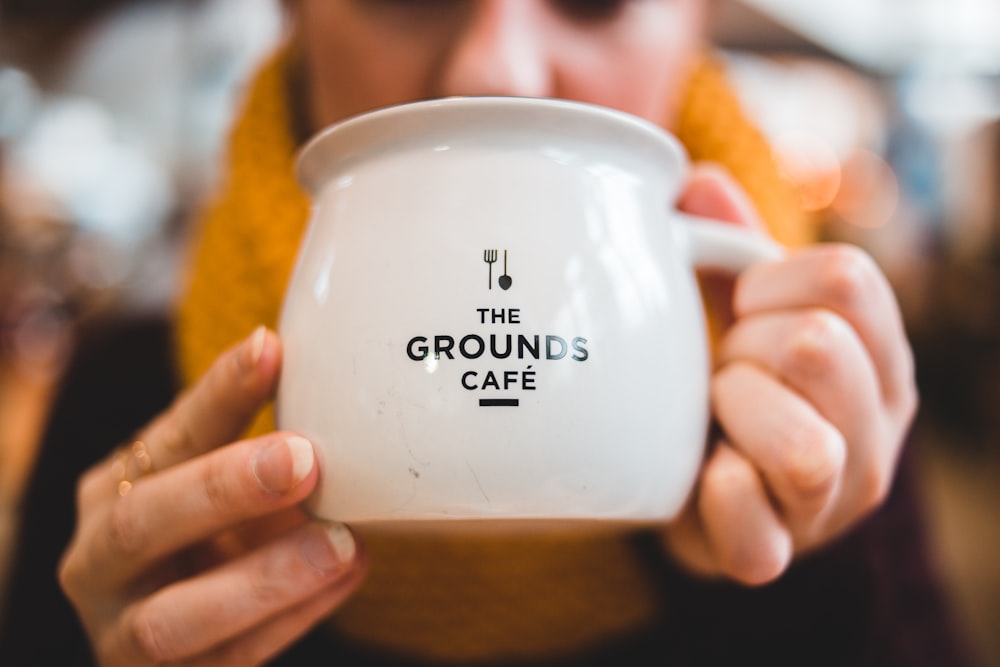 person holding The Grounds Cafe ceramic mug