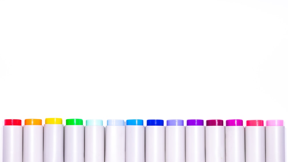une rangée de marqueurs de différentes couleurs sur fond blanc