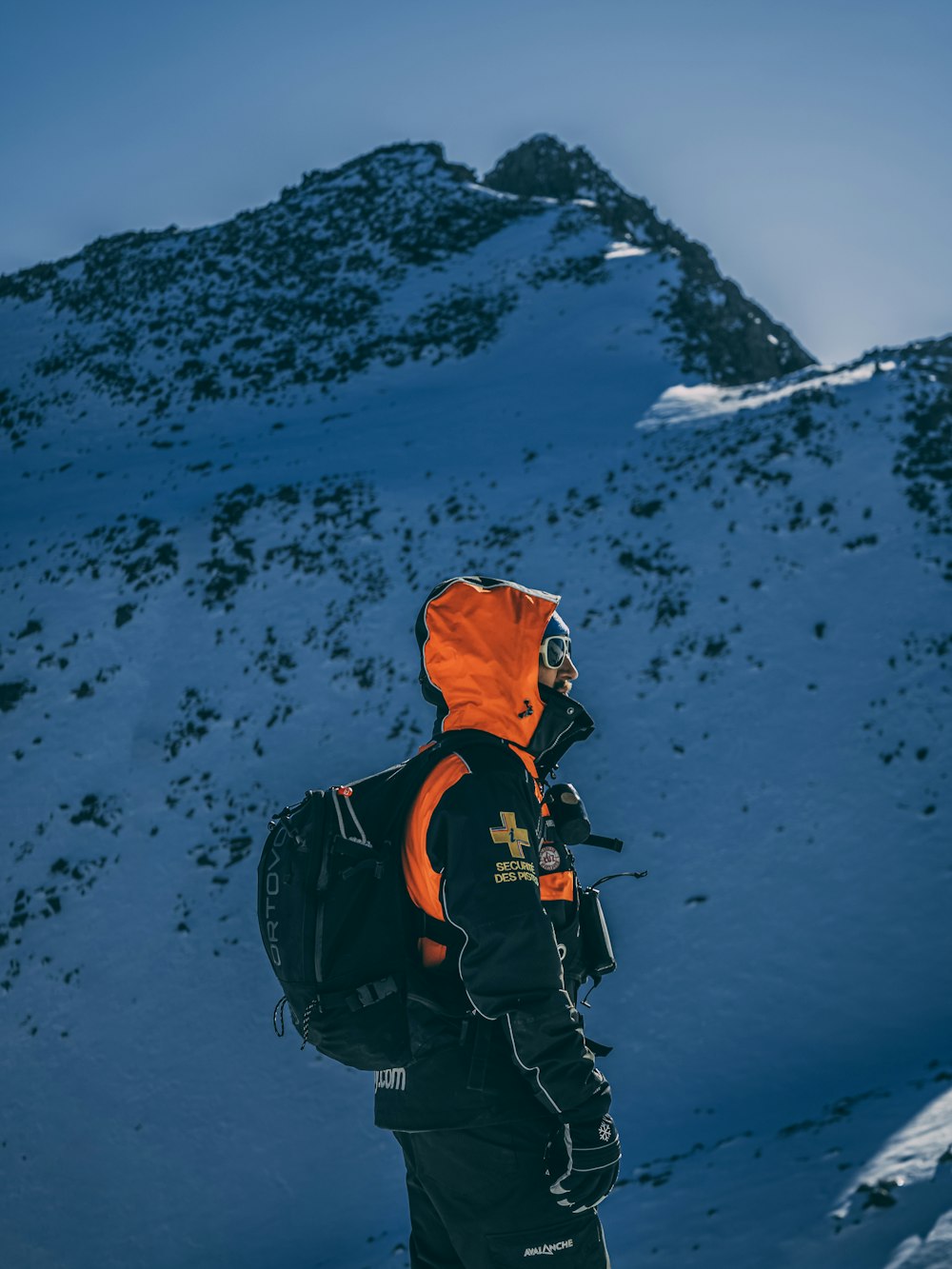 person in orange and black jacket standing on hill