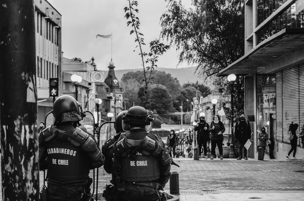 Photographie en niveaux de gris de policiers portant des armures dans la rue
